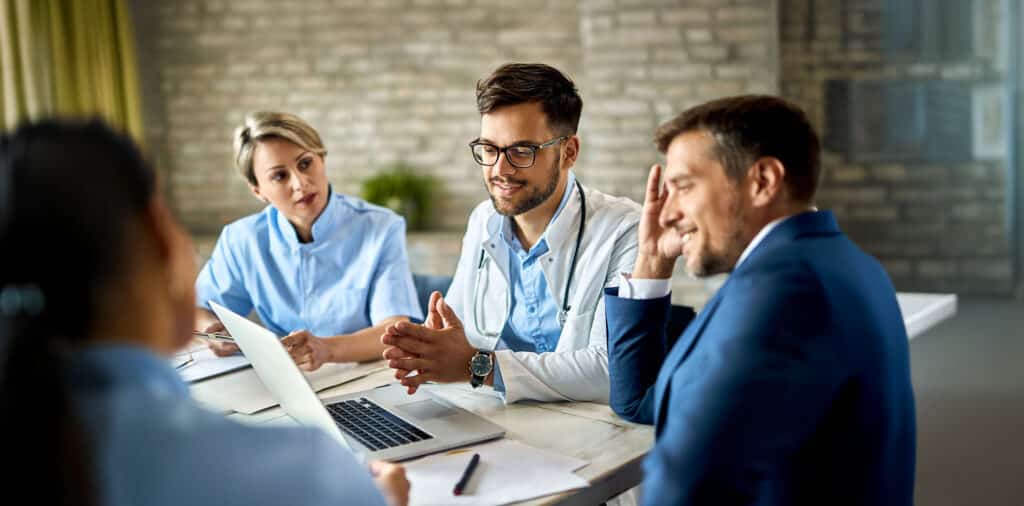 Group of healthcare workers and businessman using laptop while having a meeting