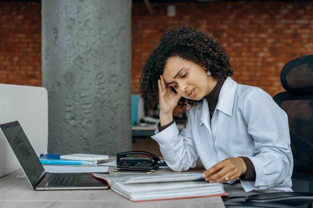 Young woman sitting at computer looking stressed. Photo by Mikhail Nilov